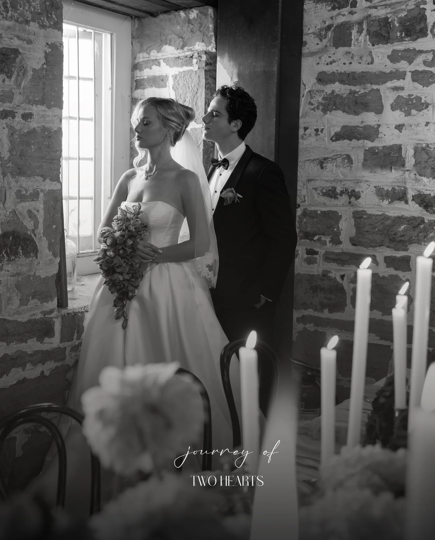 A black and white wedding portrait beside a sunlit window.